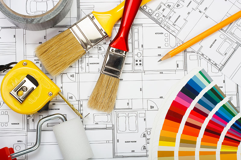 Malerutensilien und Farbpalette auf Wohnungsgrundrissplan liegend